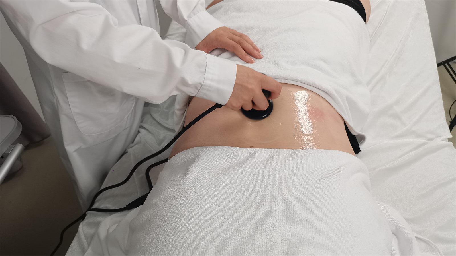 TECAR therapy session showing conductive cream and full handpiece contact on the treatment area