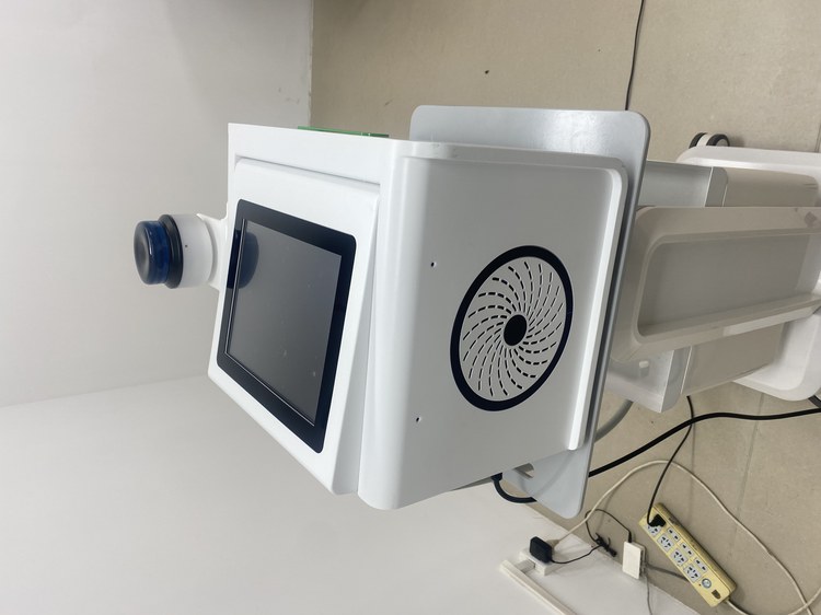 Focused shockwave applicator mounted on the housing with the cooling fan and the touch screen beside it